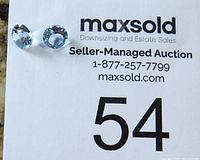 Two loose blue topaz gemstones placed on a paper with auction and lot number information.