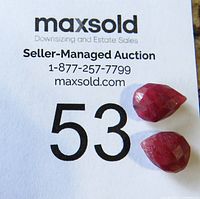 Two faceted tear-drop shaped rubies placed on a numbered auction sheet showing lot number 53.