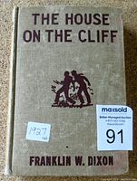 Front cover of the 1927 first edition Hardy Boys book titled 'The House on the Cliff' by Franklin W. Dixon showing typical vintage cloth cover with embossed text and illustration.