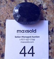 Top view of large faceted oval blue sapphire showing color and facet cuts.