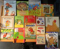 Full overhead view of 15 children's books laid out on floor showing colorful illustrated covers and varying thicknesses.