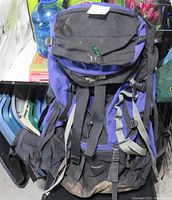Front and top view of blue and black North Face Spindrift 65 litre backpack showing multiple straps, pockets, and dirt wear at the base.