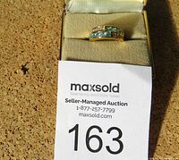 Gold ring with blue rectangular stones in a beige ring box with Maxsold auction lot label in front.