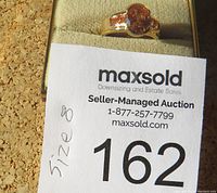 Ring size 8 shown on auction number card with central citron-colored stone and a bright gold-tone band.