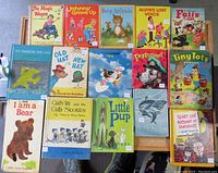Full view of 16 vintage children's books laid out, showing various colorful covers with illustrated characters and scenes.