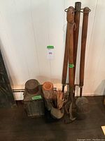 Full view of the fireplace tool set, lantern, log-shaped match container, and pottery vessel with matches shown against a white wall on a dark floor.