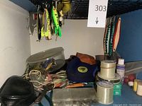 Wide view showing fishing lures hanging from rack, plastic spools of fishing line, hand tools, and container with assorted fishing hooks and lures