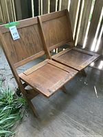 Front angled view of wooden folding bench showing two seats and backrests in upright position