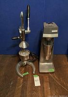 Photo of both items, the chrome manual citrus press and the Hamilton Beach malt maker with cup