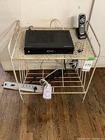 Front view of metal shelf with items on top and wooden floor underneath.