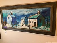 Front view of the painting on board showing village houses in blue tones within a wooden frame.