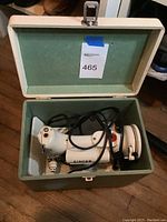 Open green and white carrying case showing white Singer sewing machine inside