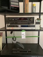 Full shelf showing Technics deck on top, Betamax player below, remote at right, CDs visible at far left