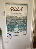 Framed UCLA poster hanging on a wall showing the campus art and map details