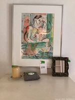 Overall view of lot showing framed print, candle, air purifying bag, and mirror on surface