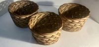 Photo shows 3 round wicker nesting baskets arranged in a line with a visible woven pattern and natural wood color.