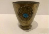 Front view showing the side of the antique metal cup with a blue turquoise colored stone in the center of the embossed circular accent.