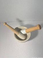 Photo of unglazed porcelain mortar with two beech wood handled pestles resting in it, showing size and condition.