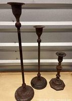 Front view of the three metal Anthropologie candle holders showing their varying heights and detailed bases