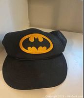 Front angled view of the black vintage Batman cap showing the yellow bat logo embroidered on the front and the mesh back panel.