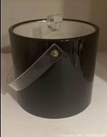 Front and side view showing the black exterior, handle, and clear knob on lid