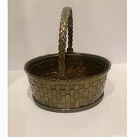 Front view of the oval brass woven basket highlighting the braided handle and woven pattern