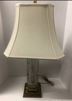 Front view of lamp showing cream fabric lampshade with slight base tilt visible.