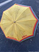 Top view of yellow umbrella canopy showing Kodak Film logos and multicolor border stripes, with visible stains and wear.
