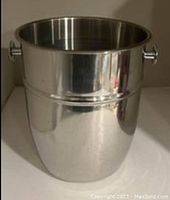 Front view of the large silver-tone metal ice bucket showing the smooth finish and cylindrical shape with side handles.