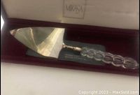 Close-up image of vintage Mikasa cake server showing silverplated blade and clear crystal handle inside original box.