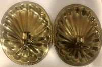 Close-up photo of one solid brass sconce showing scalloped, radiating fluted design with central candle holder