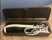 Electric slicing knife stored inside brown plastic case, showing the handle and power cord.