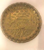 Top view of the vintage round brass tray showing embossed city scene with domed building and minarets.