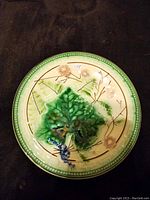 Top view of majolica plate showing green leaf centerpiece and floral pattern