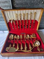 Full open view of the wooden case lined with red velvet, holding the silverplate silverware set arranged neatly.