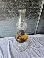 Full view of the oil lamp showing amber glass midsection and clear fluted base with clear glass chimney on top
