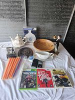 Overview of all items arranged on a table showing vintage kitchenware, games, candles, and a figurine.