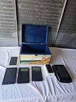 Open painted wooden box with vintage electronics displayed in front on white surface