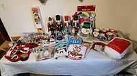 Full view of Christmas decor on table including nutcrackers, mugs, ornaments, snow globes, stockings, and wall art