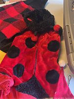 Ladybug and dog sweater costume laid flat showing colors and textures