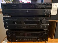 Front view of stacked Kenwood CD player, Yamaha AV receiver, and Kenwood stereo receiver showing model details and control panel layout