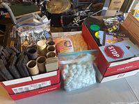 Box with assorted crafting and educational materials including cardboard tubes, cotton balls, foam pieces, and laminated signs such as a STOP sign.