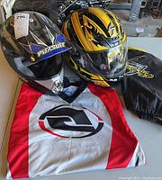 Motocross helmets and shirt arranged on table, showing overall lot items