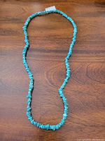 Full view of turquoise chip bead necklace laid flat to show length and bead arrangement.