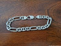 Full view of the sterling silver curb link men's bracelet laid flat showing links and lobster claw clasp.