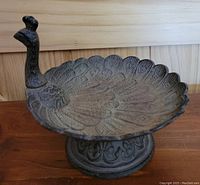 Angled side view showing peacock figure and detailed feather pattern of dish.