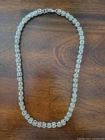 Full view of the 18-inch sterling silver Byzantine link chain necklace laid flat on a wooden surface showing the entire chain.