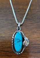 Close-up showing turquoise stone set in sterling silver pendant with decorative leaf detail.