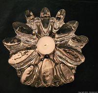 Top view of vintage glass trivit hot plate showing intricately shaped clear glass with central tea light candle holder empty.