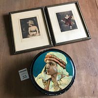 Photo showing two framed vintage portrait prints alongside the round metal candy tin featuring Rudolph Valentino.